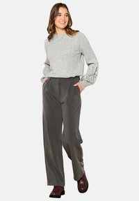 Gray knit sweater with puffed sleeves, paired with high-waisted gray trousers. Setting features dark burgundy ankle boots.