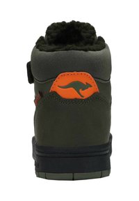 Grüner halboffener Schuh mit schwarzem Profil. Verfügt über ein weiches Innenfutter, ein orangefarbenes Känguru-Logo und einen Klettverschluss für einen sicheren Sitz.