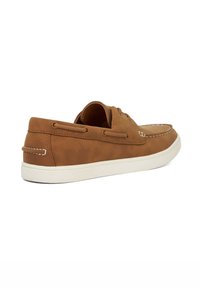 Brown leather boat shoe with white stitching and rubber sole, featuring a low silhouette and lacing detail on the sides.