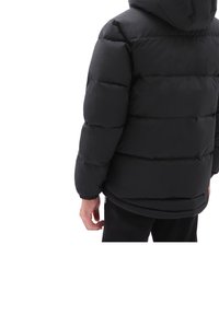 Persona con una chaqueta negra acolchada con capucha y puños elásticos, vista desde atrás contra un fondo blanco.