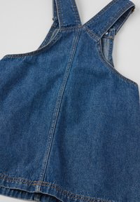 Denim-ylihaalari leveillä olkaimilla ja klassisella leikkauksella. Viimeistelty kontrastivärillä ompeleilla ja hieman haalistuneella sinisellä värillä. Liukas pinta.