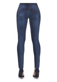 Wąskie dżinsy w ciemnoniebieskim denimu, z umiarkowanym stanem, klasycznymi tylnymi kieszeniami i gładką fakturą. Połączone z czarnymi butami na wysokim obcasie.