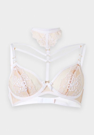 Kreemjas pitsrinnahoidja valgete reguleeritavate rihmade ja esise rakmete detailiga, millel on lilleline tikand ning väike sobiv pitsist aksessuaar üleval.