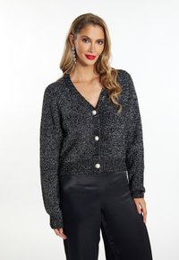 Cardigan nero e argento con scollatura a V, maniche lunghe e tre bottoni in perla. Materiale a maglia testurizzato con design cropped.