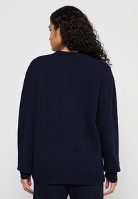 Navyblauer Strickpullover mit lockerer Passform, Rundhalsausschnitt, gerippten Ärmelbündchen und Saum. Die Textur wirkt weich mit einem dezenten Webmuster.