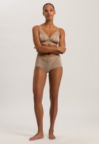Beige lingerieset met een zachte, gladde bralette met kantaccenten en hoogstaande slipjes met ingewikkelde kantdetails.