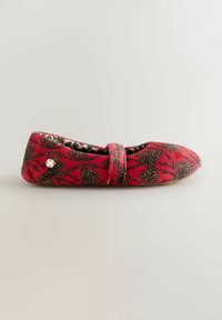 Piros laposcipő virág- és leopárdmintás dizájnnal, melynek elején pánt található, és sima szövetből készült. Lapos talp.