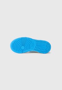 Blue rubber sneaker sole with textured grip patterns, circular and line details, and a logo. White midsole contrast with the vibrant color.