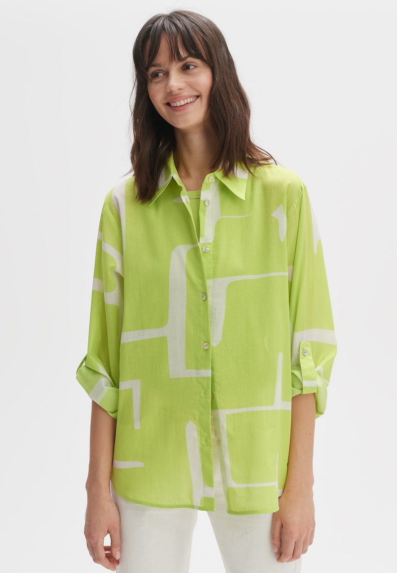 Green patterned button-up shirt with rolled sleeves, featuring abstract white geometric shapes, lightweight fabric, and a classic collar.