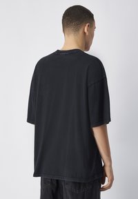 Zwarte oversized T-shirt van katoen, met een ronde halslijn, korte mouwen en een eenvoudige uitvoering met subtiele textuur.
