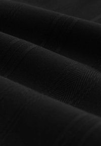 Schwarzer Stoff mit einer glatten Textur, der subtile horizontale Streifen und einen leichten Glanz aufweist, dargestellt in überlappenden Falten.