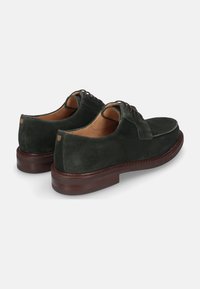 Donkergroene suède schoenen met een gladde structuur, voorzien van een vetersluiting, bruine leren binnenzolen en een stevige bruine rubberen zool.