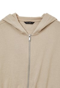 Felpa beige realizzata in morbido tessuto, con chiusura frontale a zip, cappuccio regolabile e polsini a costine. Etichetta con la scritta "CALLIOPE" e taglia "S."