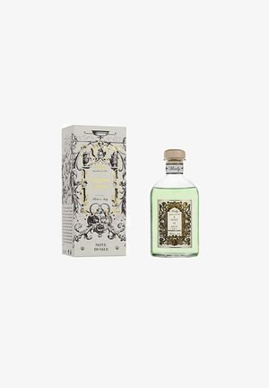 Bottiglia di liquido verde etichettata Note di Sale con cornice decorativa ornata in oro e nero, accanto a una scatola decorativa bianca e oro coordinata.