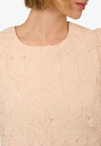 Abito rosa chiaro con un motivo floreale testurizzato, dotato di scollatura rotonda e bordi grezzi, realizzato in un tessuto morbido e trasparente.