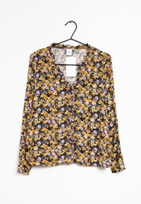 Blusa floreale con maniche lunghe, caratterizzata da uno sfondo nero e un motivo di fiori gialli e viola. Ha un collo a V e dettagli con bottoni.