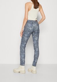 Stretch denimbyxor i blått med vitt paisleymönster; slimmad passform, medelhög midja och avslutad med en bakfickdesign.