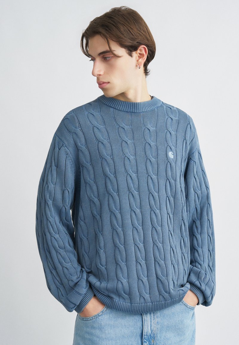 Μπλε πουλόβερ πλεκτό με στρογγυλή λαιμόκοψη, με υφή και ριμπ μανσέτες. Φοριέται καθημερινά πάνω από ανοιχτόχρωμο τζιν.