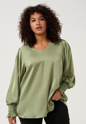 Groene satijnen blouse met een V-hals, volumineuze lange mouwen en geplooide manchetten. Glad textuur met een losse pasvorm en subtiele glans.