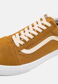 Baskets en daim marron avec des lacets crème, dotées d'une semelle en caoutchouc blanche et d'une bande latérale crème distinctive. Tiges texturées pour plus de profondeur.