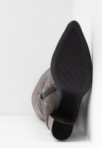 Bottine à bout pointu et talon, avec texture en cuir de serpent et fermeture éclair latérale, semelle dotée d'un motif de bande de roulement en zigzag.