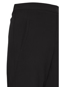 Pantalon noir ajusté avec une poche fendue sur le côté et une taille cintrée sur un fond uni.