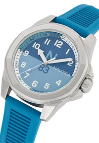 Nautica kell, millel on roostevabast terasest korpus, sinine gradientide dial, suured valged numbrid ja tekstureeritud sinine kummirihm. Hõbedased aksessuaarid.