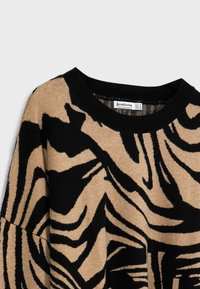 Sweter dzianinowy z beżowo-czarnym wzorem zebry, okrągłym dekoltem i prążkowanymi czarnymi mankietami. Miękka tekstura z luźnym krojem.