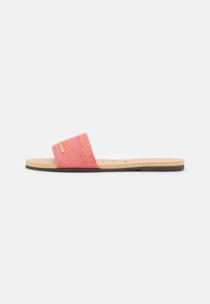 Sandale plate avec semelle beige et large bride tissée rose traversant le pied, montrée de côté sur fond blanc.