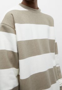 Sweatshirt en mélange de coton doux, avec des rayures horizontales en beige clair et blanc. Design à col rond avec une coupe décontractée.