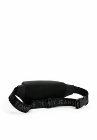 Borsa in vita nera realizzata in un materiale liscio con dettagli in rete. Presenta una cucitura spessa con il logo "TOMMY JEANS" e una fibbia in plastica.