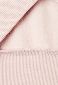 Prenda de color rosa claro con un suave forro interior y una textura acanalada en el exterior. El dobladillo presenta una costura cuidada.