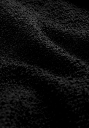 Texturovaná černá tkanina s měkkým, načechraným povrchem. Obsahuje jemné rýhy a údolí, což vytváří hloubku a vizuální zajímavost.