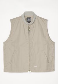 Beige ermeløs vest med ribbestrikket krage, glidelås foran, to sidelommer og et logo-patch på nedre høyre side.