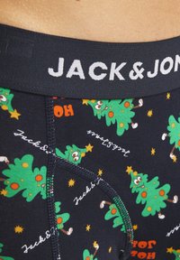 Sous-vêtements bleu marine avec un motif festif d'arbres de Noël verts souriants, d'étoiles et d'accents rouges. Ceinture élastique avec le logo "JACK & JON".