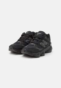 Des chaussures de sport noires avec une tige en matériaux mixtes, des panneaux en maille, un col rembourré, des lacets et une semelle extérieure épaisse.