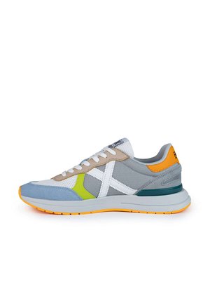 Zapatilla deportiva en gris, blanco y azul con acentos en verde y naranja. Cuenta con una parte superior de malla, cierre de cordones y suela de goma texturizada.