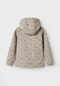 Beige vandtæt jakke med blomsterprint over det hele, hætte, elastiske manchetter og et reflekterende brandlogo i kanten. Glat tekstur.