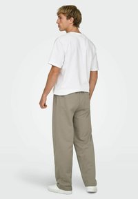 Biała koszulka z krótkim rękawem, luźne szare spodnie i białe trampki. Prosty design, miękki bawełniany materiał, minimalne detale i swobodny krój.