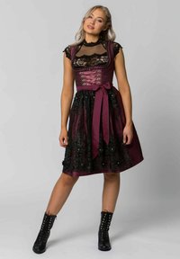 Burgunderrotes, besticktes Kleid mit taillierter Oberseite, Spitzenakzenten und ausgestelltem Rock. Betont mit einem satinierten Band in der Taille und schwarzen Stiefeln.
