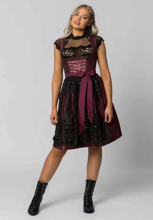 Burgunderrotes, besticktes Kleid mit taillierter Oberseite, Spitzenakzenten und ausgestelltem Rock. Betont mit einem satinierten Band in der Taille und schwarzen Stiefeln.