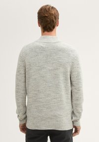 Helles graues Strickpullover mit texturiertem Finish, geripptem Kragen und Bündchen sowie einem lockeren Schnitt, der ein dezentes meliertes Muster aufweist.