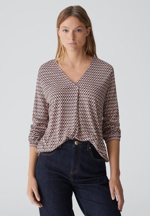 Long-sleeve, V-neck top with a checkered pattern in pink and navy. Made of soft fabric, featuring gathered sleeves and a relaxed fit.
