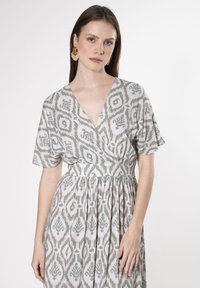 Kurzärmeliges Wickelkleid in Hellrosa und Grün mit einem abstrakten Muster. Verfügt über einen V-Ausschnitt und eine gebundene Taille für eine fließende Silhouette.