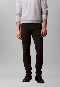 Black denim jeans with a slim fit, featuring a classic five-pocket design, reinforced seams, and subtle fading for texture.