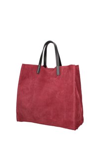 Borsa tote in suede rosso con manici in pelle nera e cuciture visibili, in piedi su uno sfondo bianco.