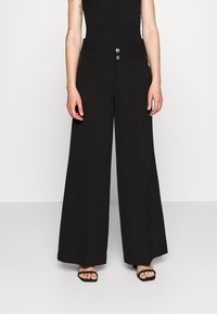 Černé kalhoty s širokými nohavicemi, s dvěma kovovými knoflíky v pase, vyrobené z hladké tkaniny, s vysokým pasem a přiléhavým střihem.