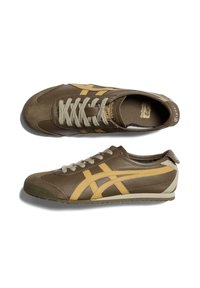 Brune lædersneakers med gule sidelister, beige detaljer, tekstureret tåhætte og lysegrå snørebånd. Slankt design med lav profil.