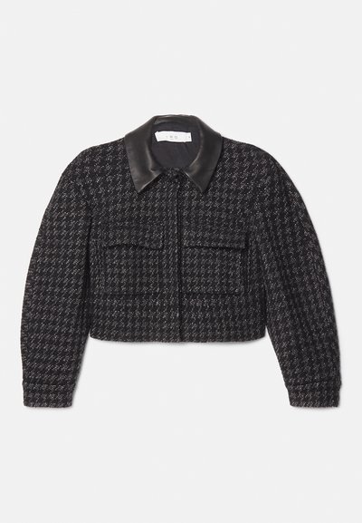 Black and white tweed cropped jacket featuring a smooth black leather collar, front zip closure, and two patch pockets. Textured fabric.