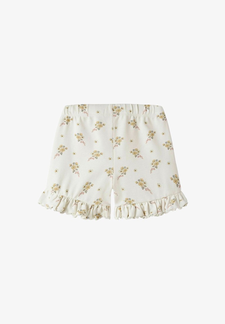 Shorts couleur crème avec motifs floraux jaunes et ourlets à volants, dotés d'une taille élastique pour un ajustement confortable.